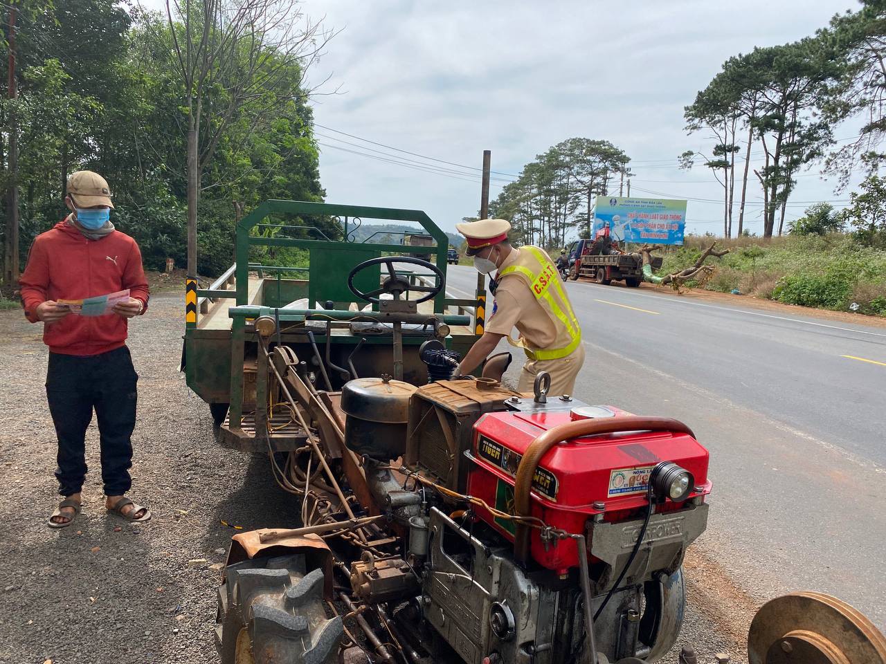 Một chủ phương tiện xe máy kéo được phát tờ rơi tuyên truyền về Luật Giao thông đường bộ.