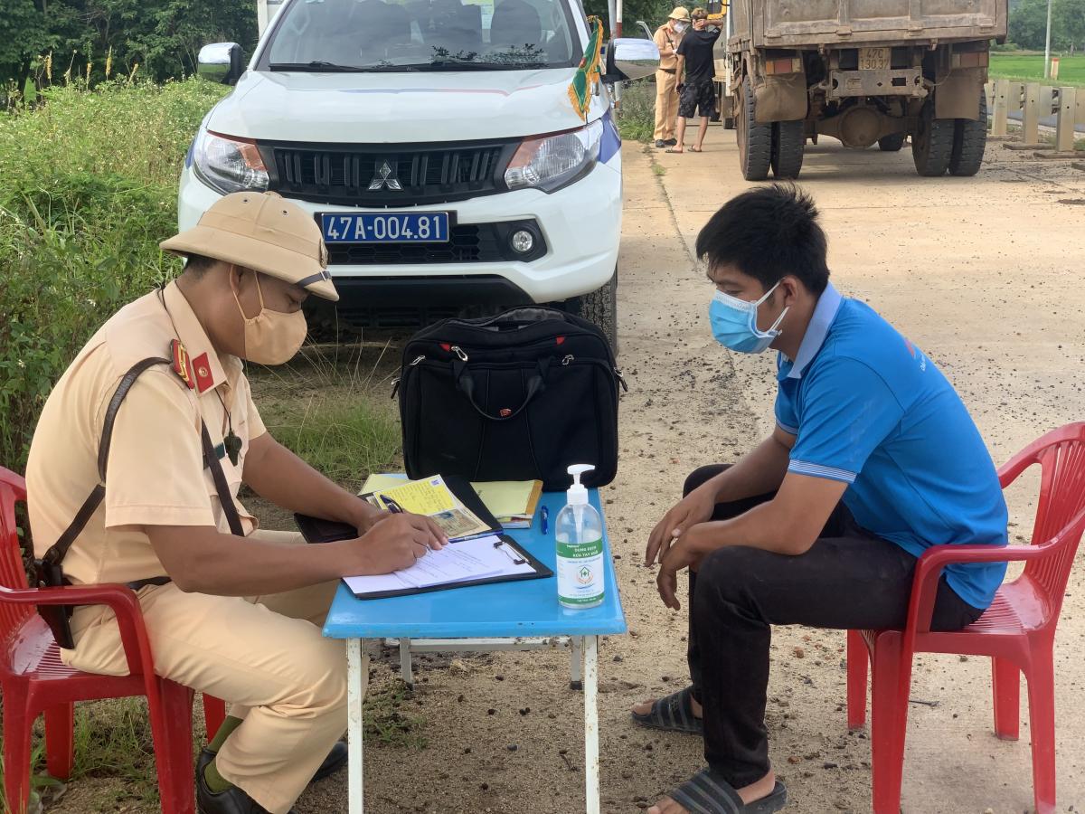 Cán bộ, chiến sĩ Đội CSGT-TT Công an huyện Krông Ana lấy thông tin dịch tễ của tài xế tại Tỉnh lộ 2 (đoạn qua xã Dray Sáp, huyện Krông Ana).